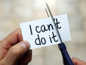 Man using scissors to remove the word can't to read I can do it concept for self belief, positive attitude and  motivation